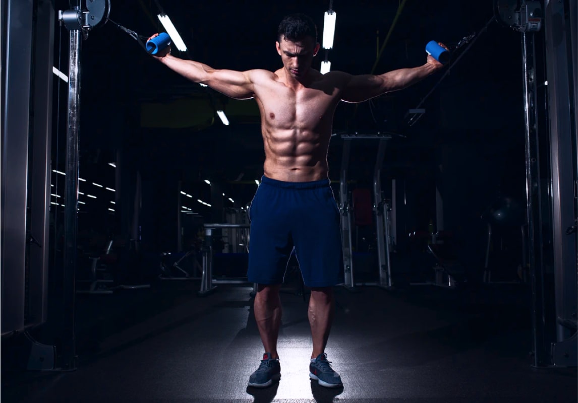 a man with abs standing in the light pulling weights