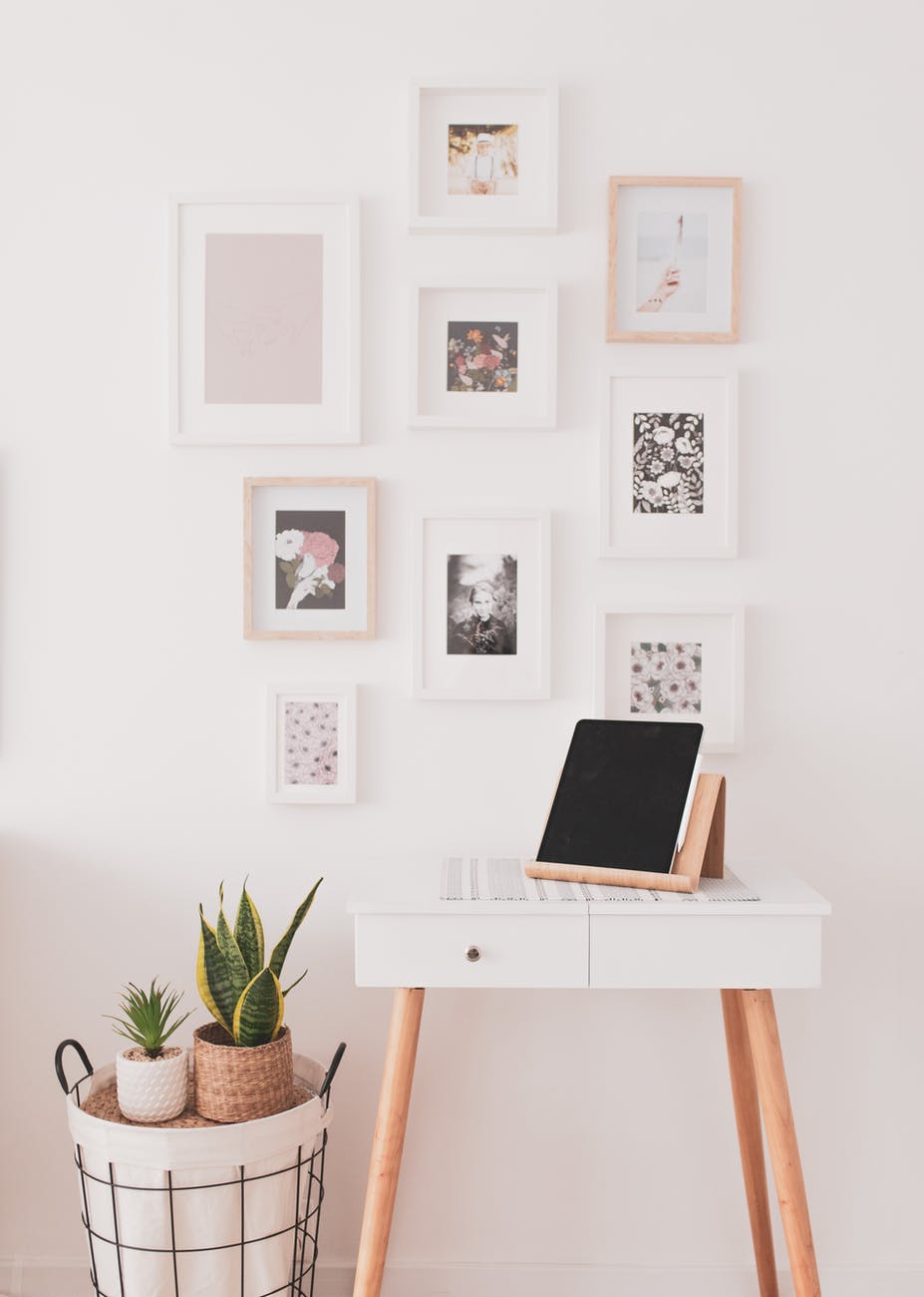 Light wall with pictures and small white desk with brown legs