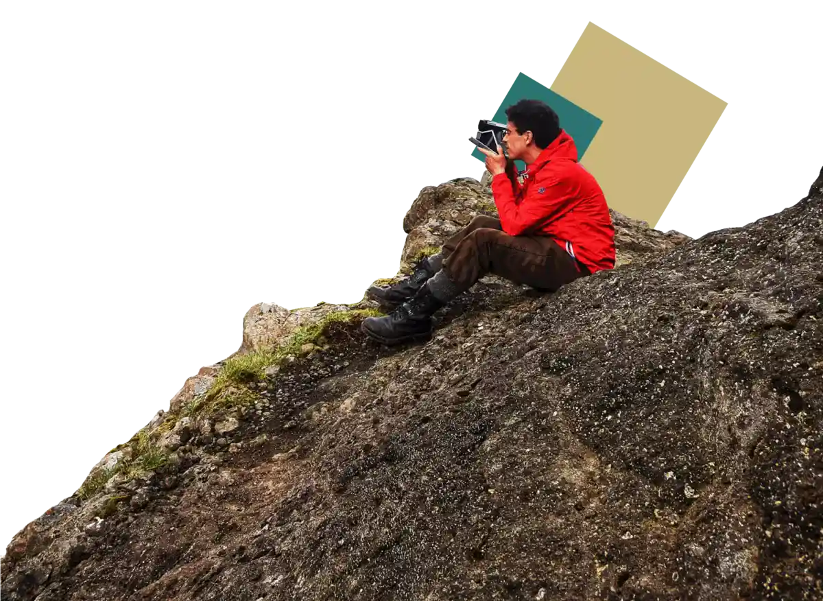 um homem se senta na montanha com uma câmera