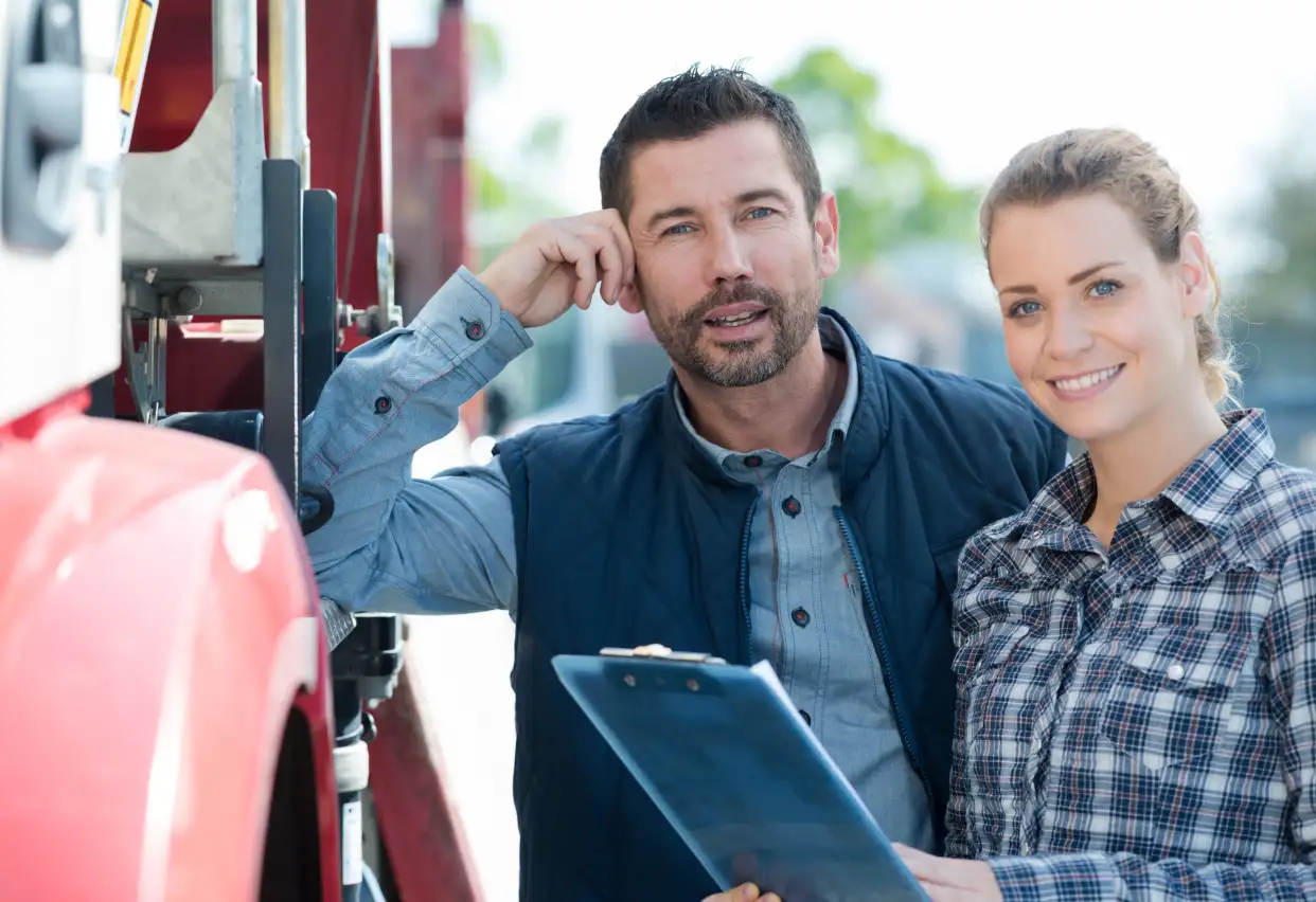 a man and a woman are standing near a truck