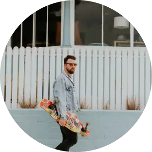 un mec à lunettes avec un skateboard dans les mains