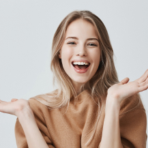 blonde woman laughing and throwing her hands in the air