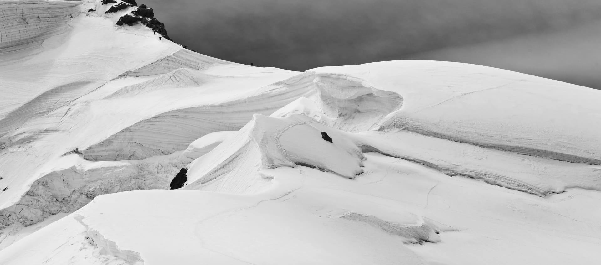 montanha coberta de neve com caminhantes subindo em uma linha