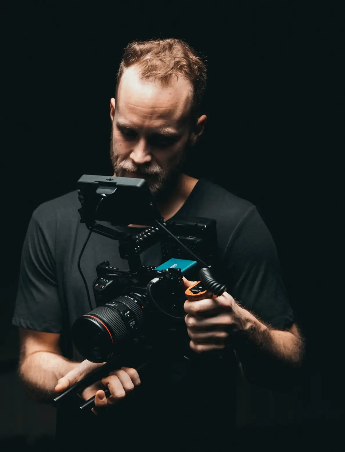 man in a dark room looking at his camera to evaluate takes that he took