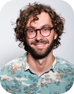 programmatore con capelli biondi ricci e barba con occhiali e camicia hawaiana