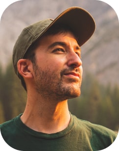  a white man with facial hair and cap hat looking at the sun