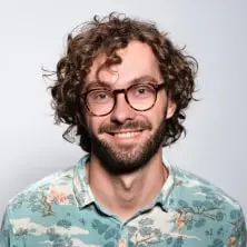 white man with curly hair and beard with glasses in a hawaiian shirt