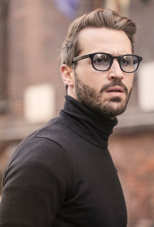 blonde male with glasses and black sweater looking confused