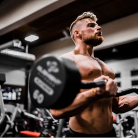 a ripped man with blonde hair and facial hair lifting weights