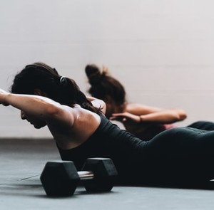 two ladies doing stretching exercises with dumbells