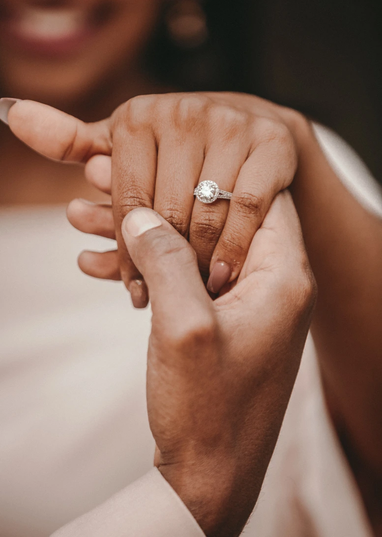 Verlobungsring an der Hand der Braut, der vom Bräutigam gehalten wird