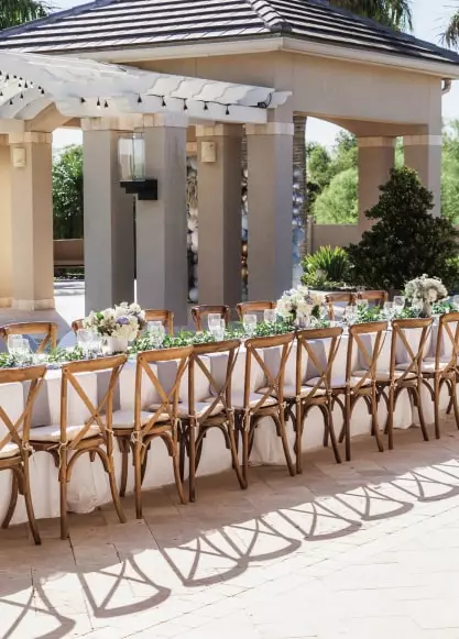 stół pokryty kwiatami i jedzeniem przygotowanym na wielką ceremonię na świeżym powietrzu