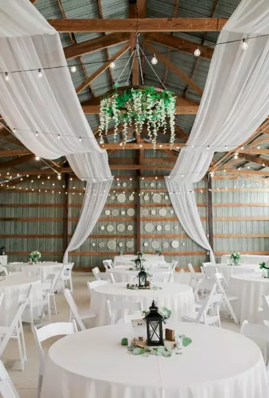 mesas cobertas com pano branco e lanternas para uma ceia dentro de casa