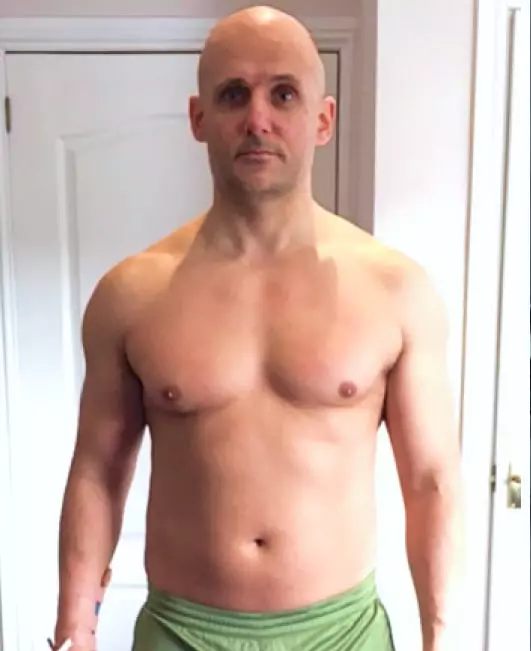 a bald man in green shorts posing to a mirror