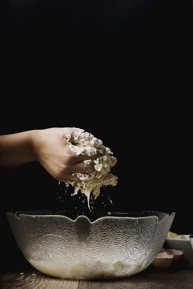 chef making a dough for pasta in a bowl using flower and yeast