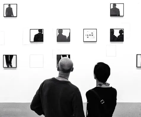 a man and a woman look at a photo attached to the wall