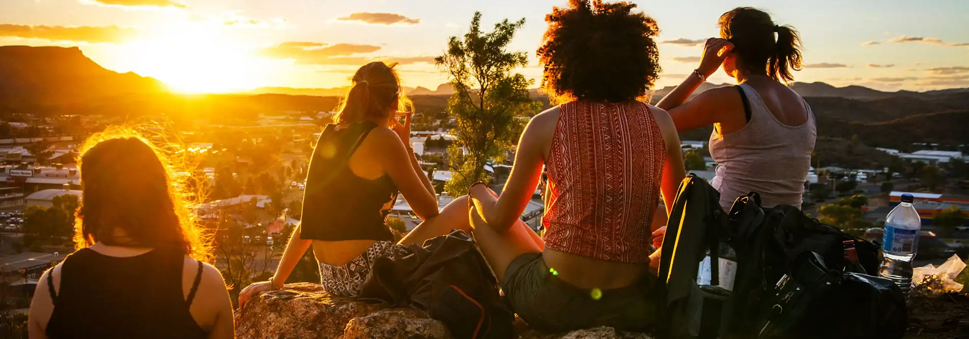 friends sitting on a mountain looking at the city