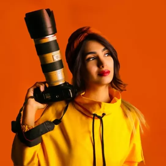 a girl in a yellow jacket with a camera
