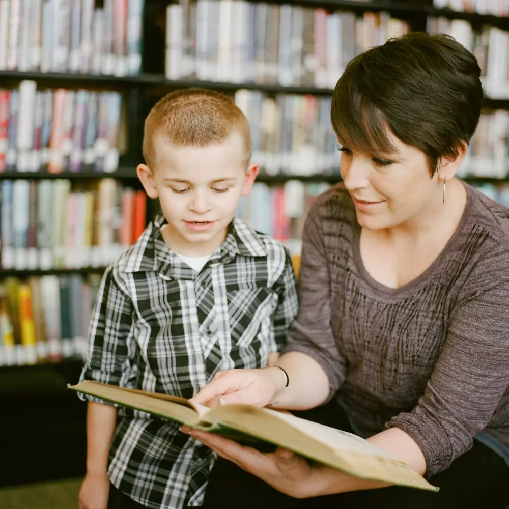 El maestro le muestra al niño un libro.