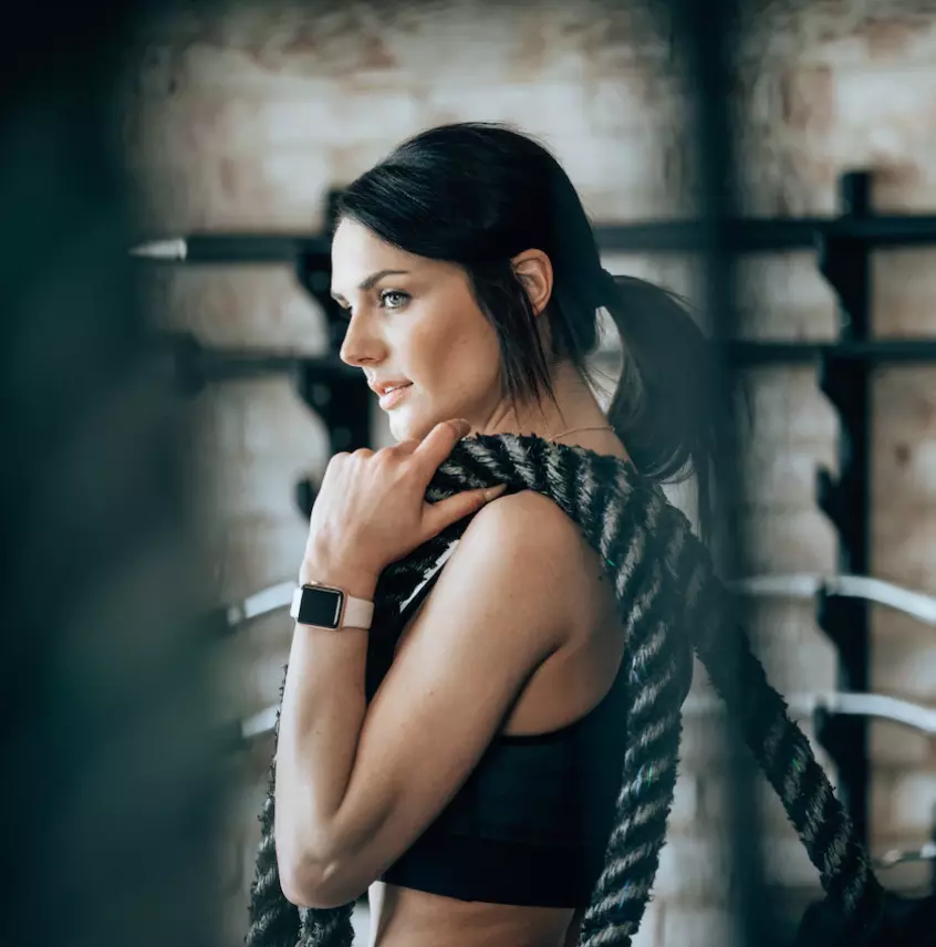 Brunette girl in the gym with ropes on her shoulder