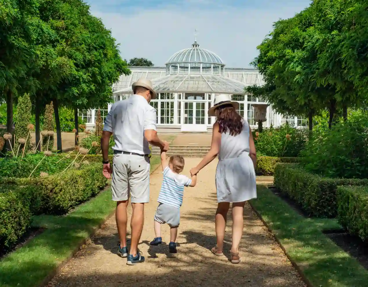 a family with a kid taking a walk in the park surrounded by plants