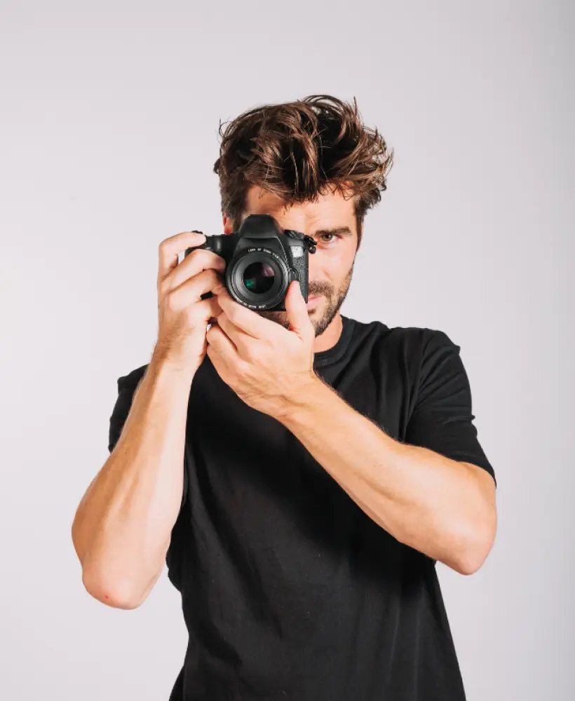 A man in a black T-shirt holds a camera