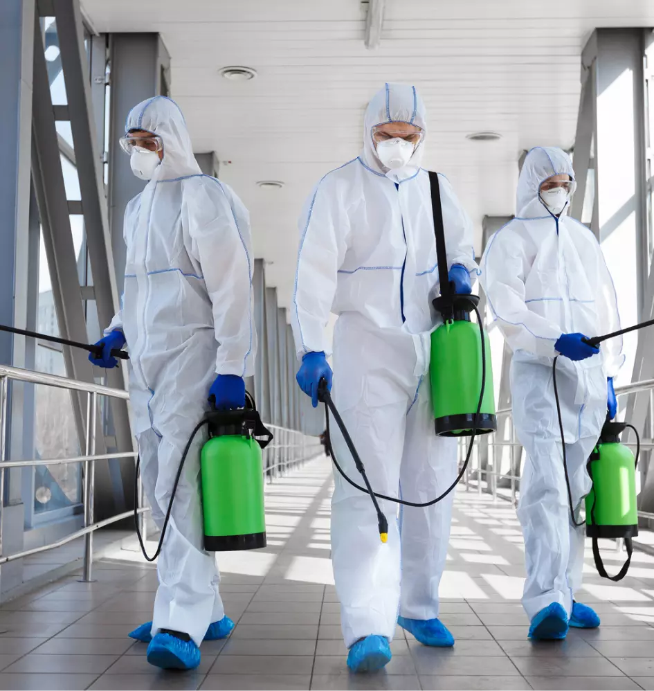 three workers in protective suits carry out disinfection
