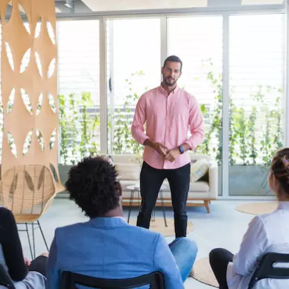 a man in a pink shirt talking to his colleagues