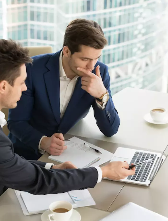 two men sitting at a laptop