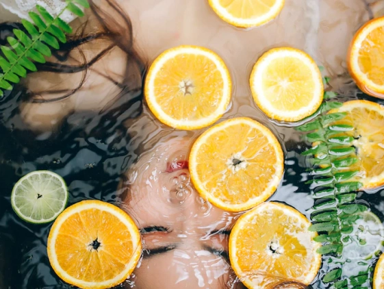 woman submerged under water with floating lemon slices and green detox leafs