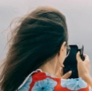 une femme par temps venteux prend une photo avec son téléphone