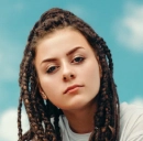 girl with dark dreadlocks looking stoic in front of the camera
