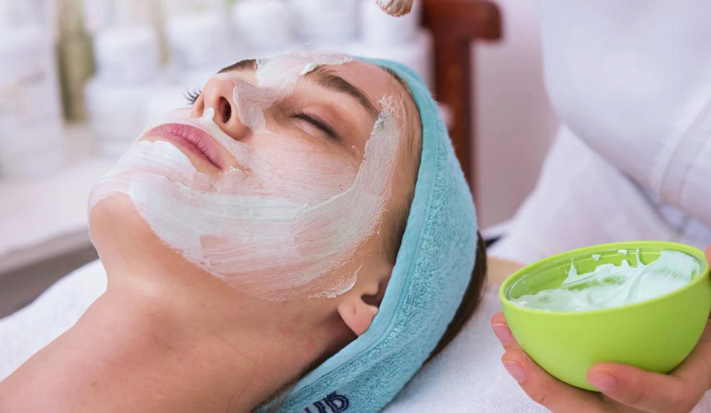 woman having a facial mask applied with a hot towel treatment