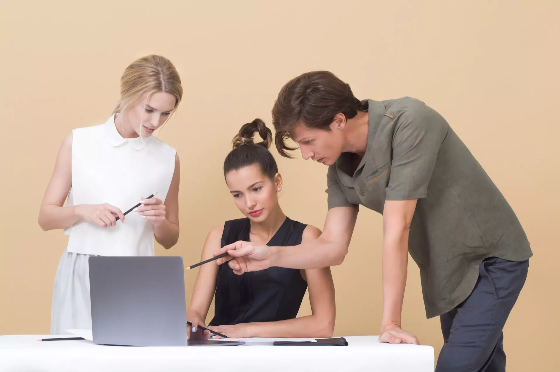 two girls and a man looking at a laptop