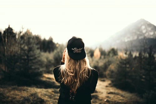 una ragazza vicino agli alberi che guarda la montagna