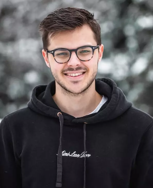 ein Mann in einem schwarzen Sweatshirt und einer Brille