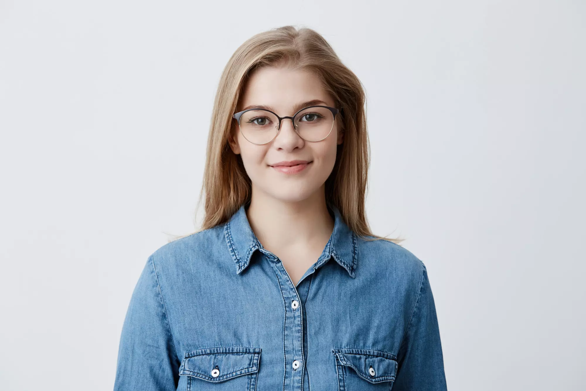 brown-haired woman in a denim shirt and glasses