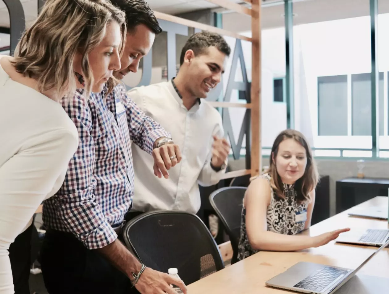 a group of people looking at a laptop and discussing something