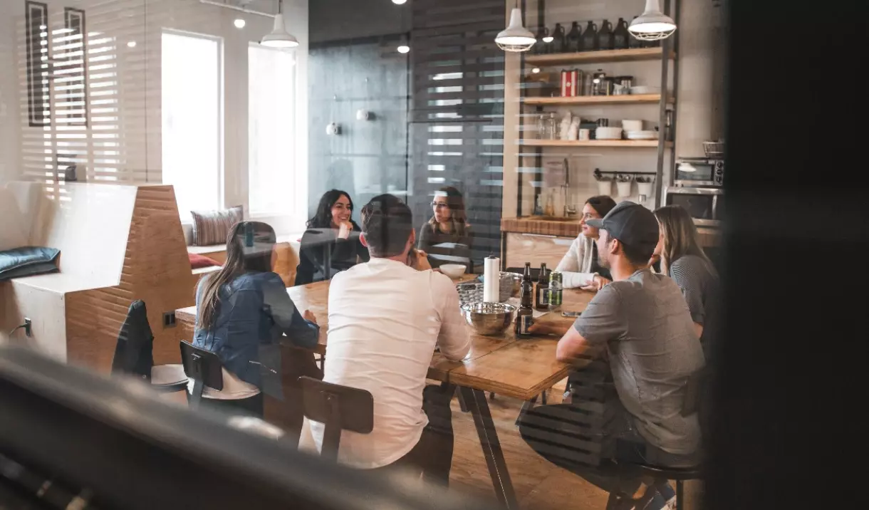 a group of people sit at a table in an institution and have a conversation