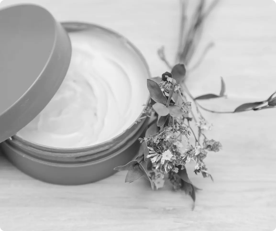 a small bouquet of wildflowers lies next to an open jar of cream