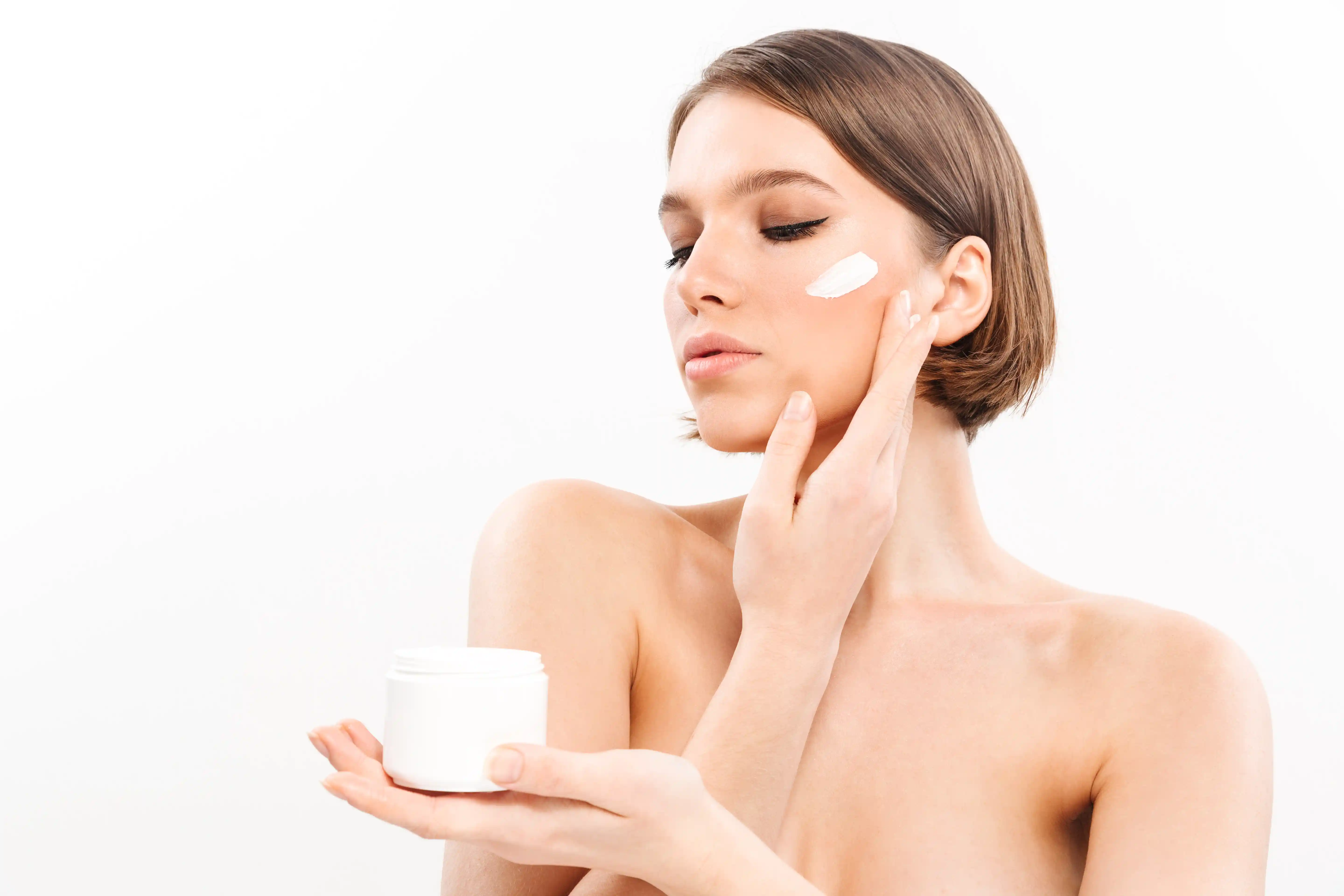 girl in front of a mirror applying cream to her face