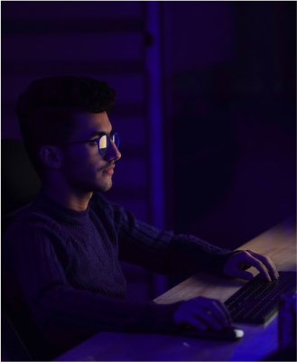 guy sitting in a dark room in front of a bright computer screen