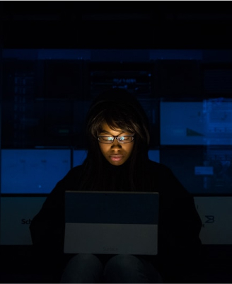 girl sitting in a dark room in front of a bright computer screen