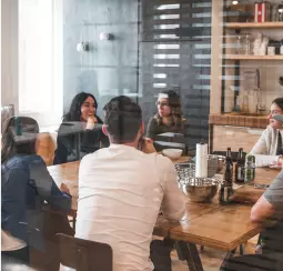 a group of people sit at a table in an institution and have a conversation