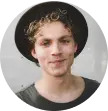 young guy with white curly hair wearing a black hat