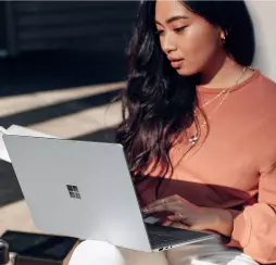 brunette in a peach jacket working at a laptop