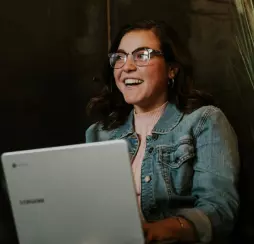 brown-haired girl in glasses and a denim jacket, laughing