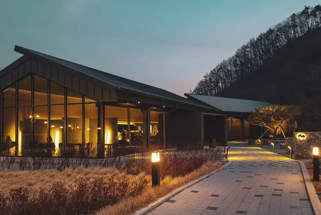 modern one-story house with lights on at sunset