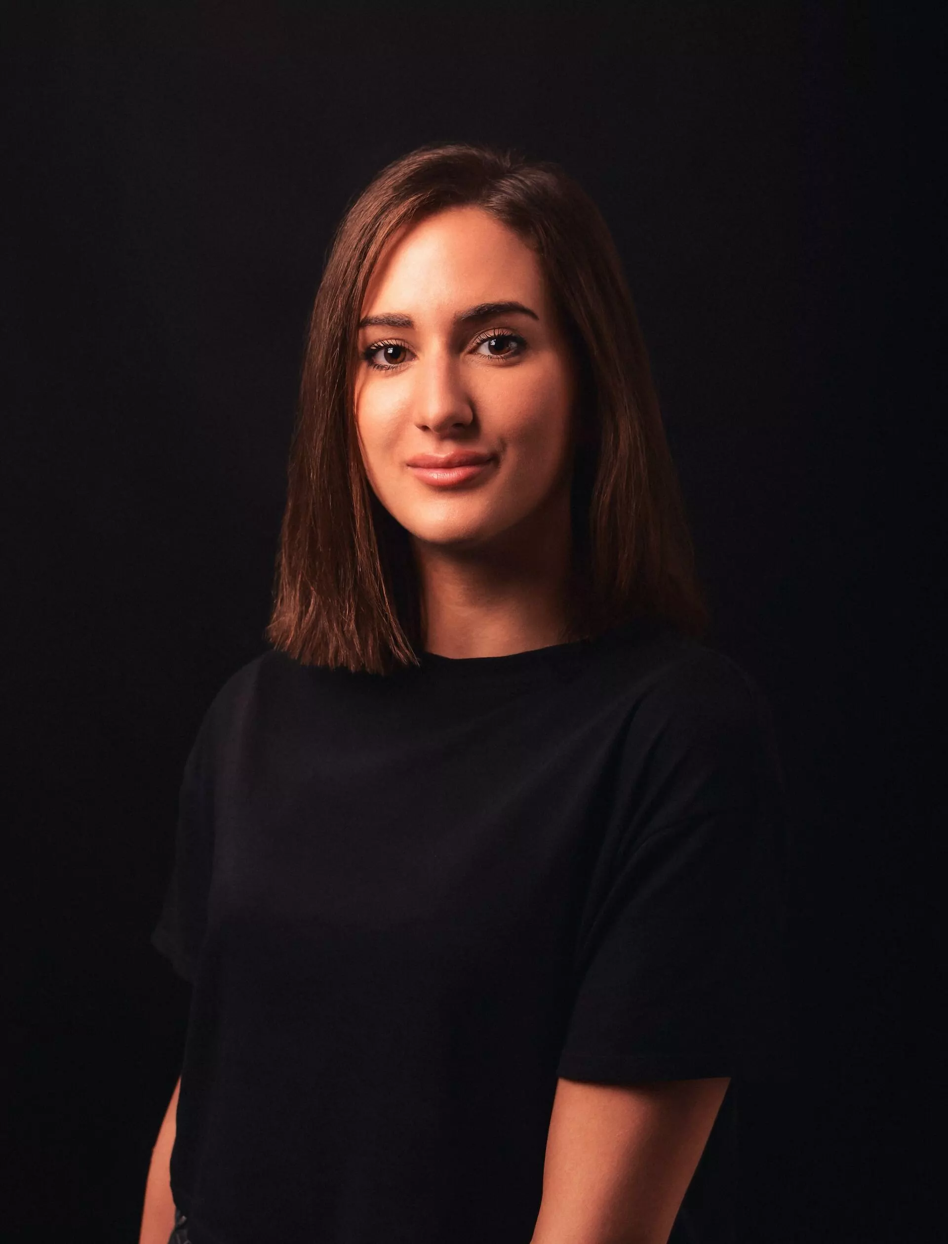 brown-haired girl in black clothes in a dark room