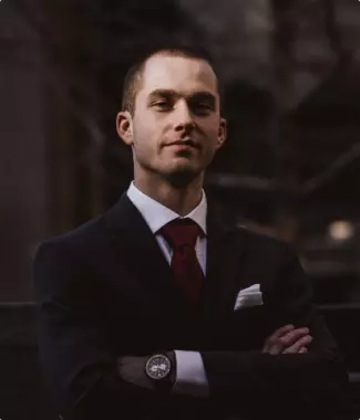 a guy in a suit and tie stands with his arms folded on his chest